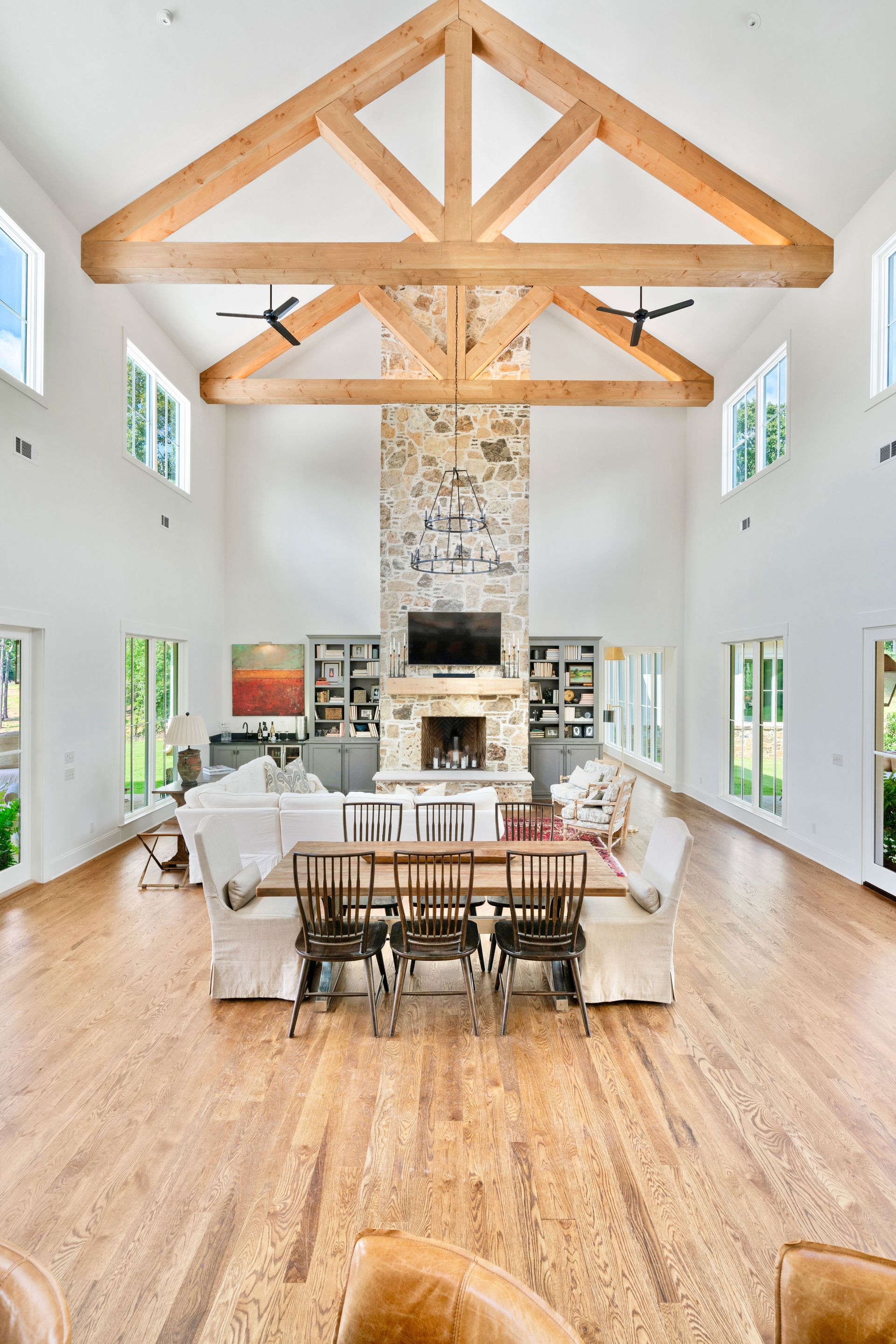 Spacious living room with wood beams, stone fireplace, and light wood flooring.