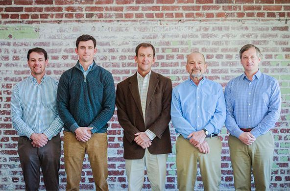 A group of men are posing for a picture in front of a brick wall.