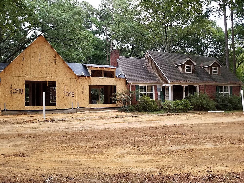 Exterior (In Progress) - House under construction: Wood framing next to finished brick home. Dirt lot.