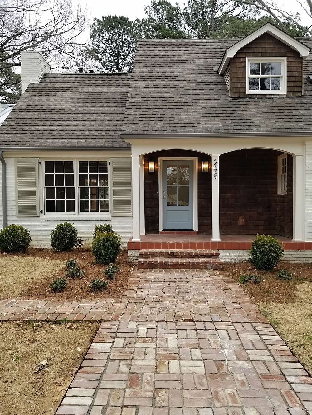 Front Door (After) - Charming white cottage with brick walkway, blue door, and brown roof.