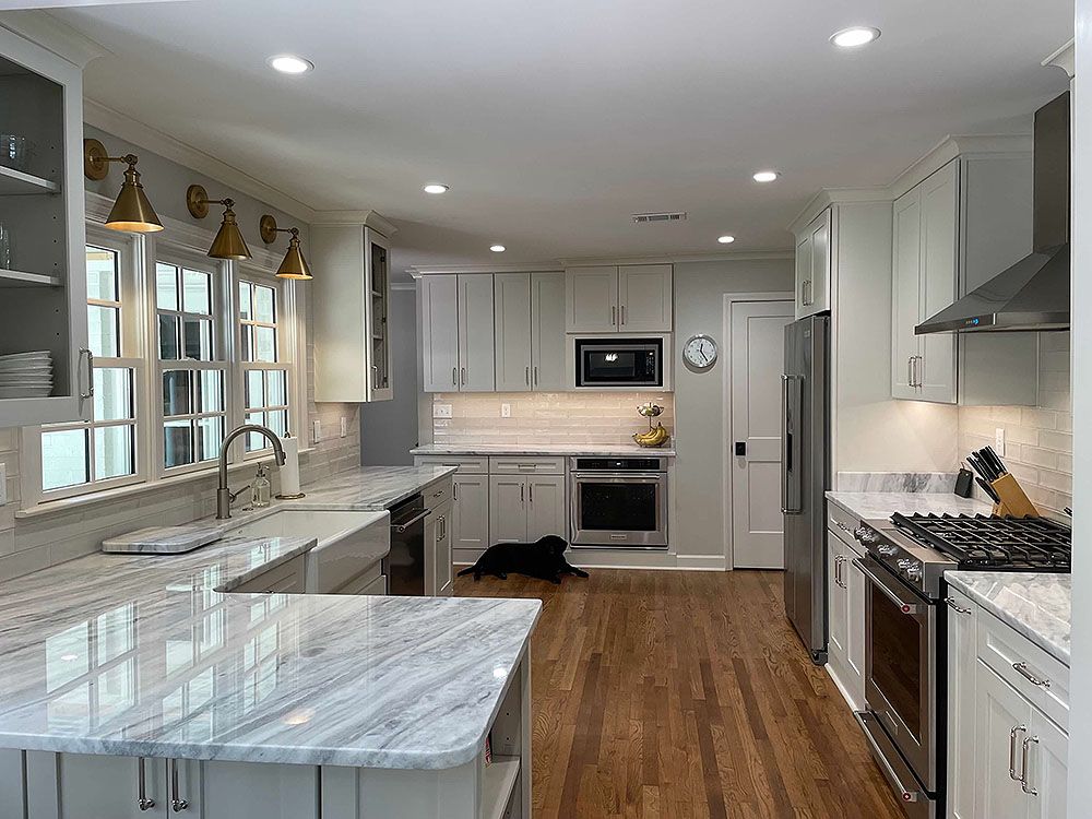 Kitchen (After) - Spacious white kitchen with granite countertops, stainless steel appliances, and a dog lying on the floor.