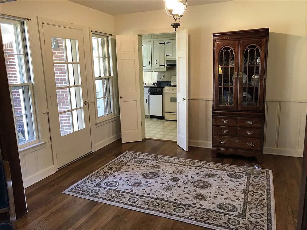 Kitchen (Before) - Dining room with glass doors, rug, hutch, and view into the kitchen.