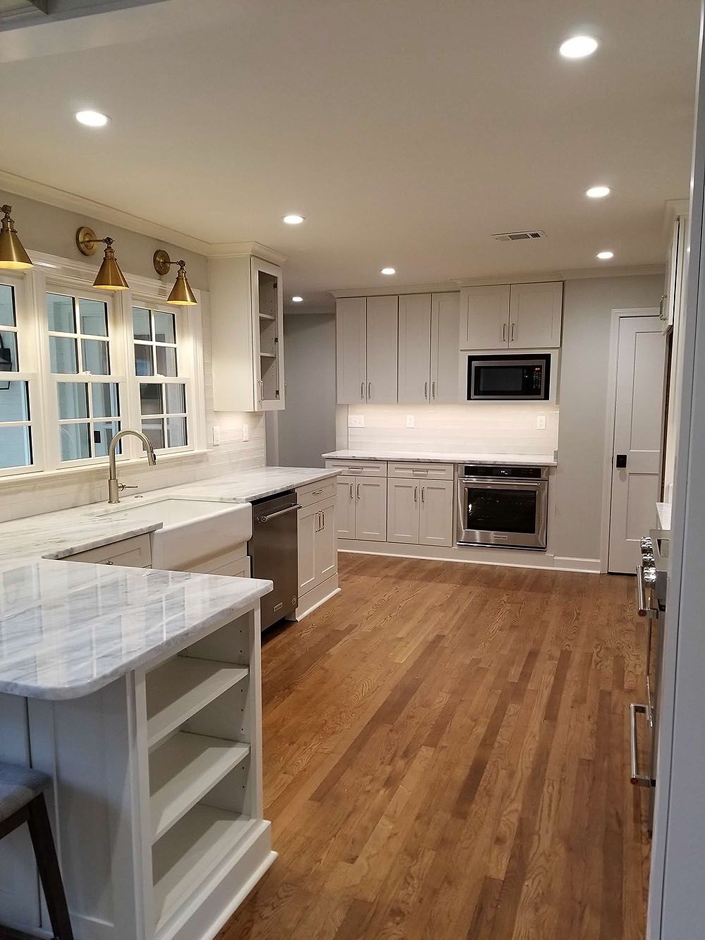 Kitchen (After) - White kitchen with wooden floors and stainless steel appliances.
