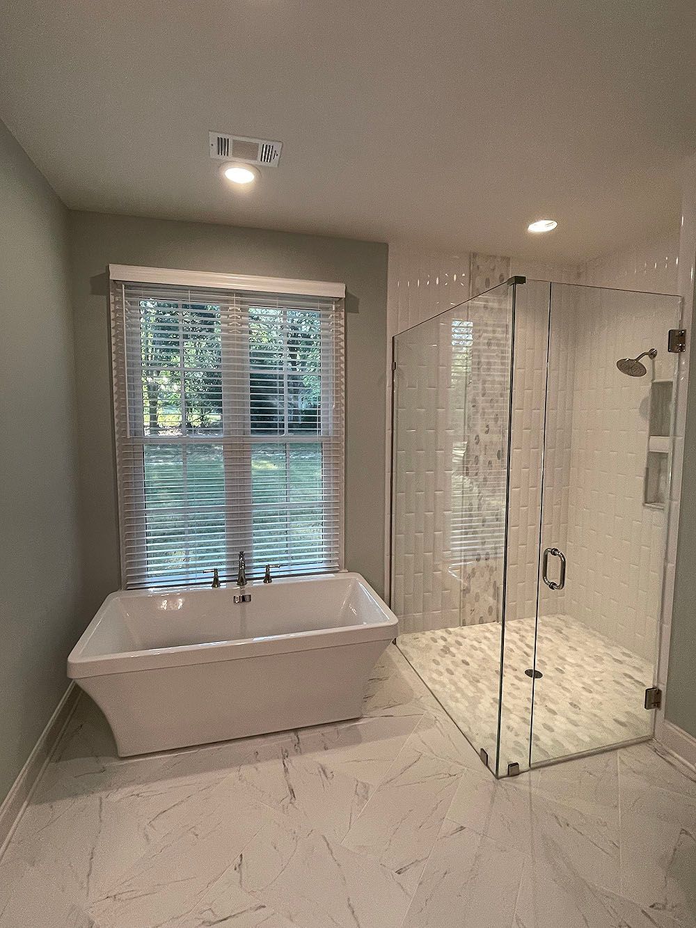 Master Bath 1 - Bathroom with white freestanding tub, glass shower, and window with blinds.