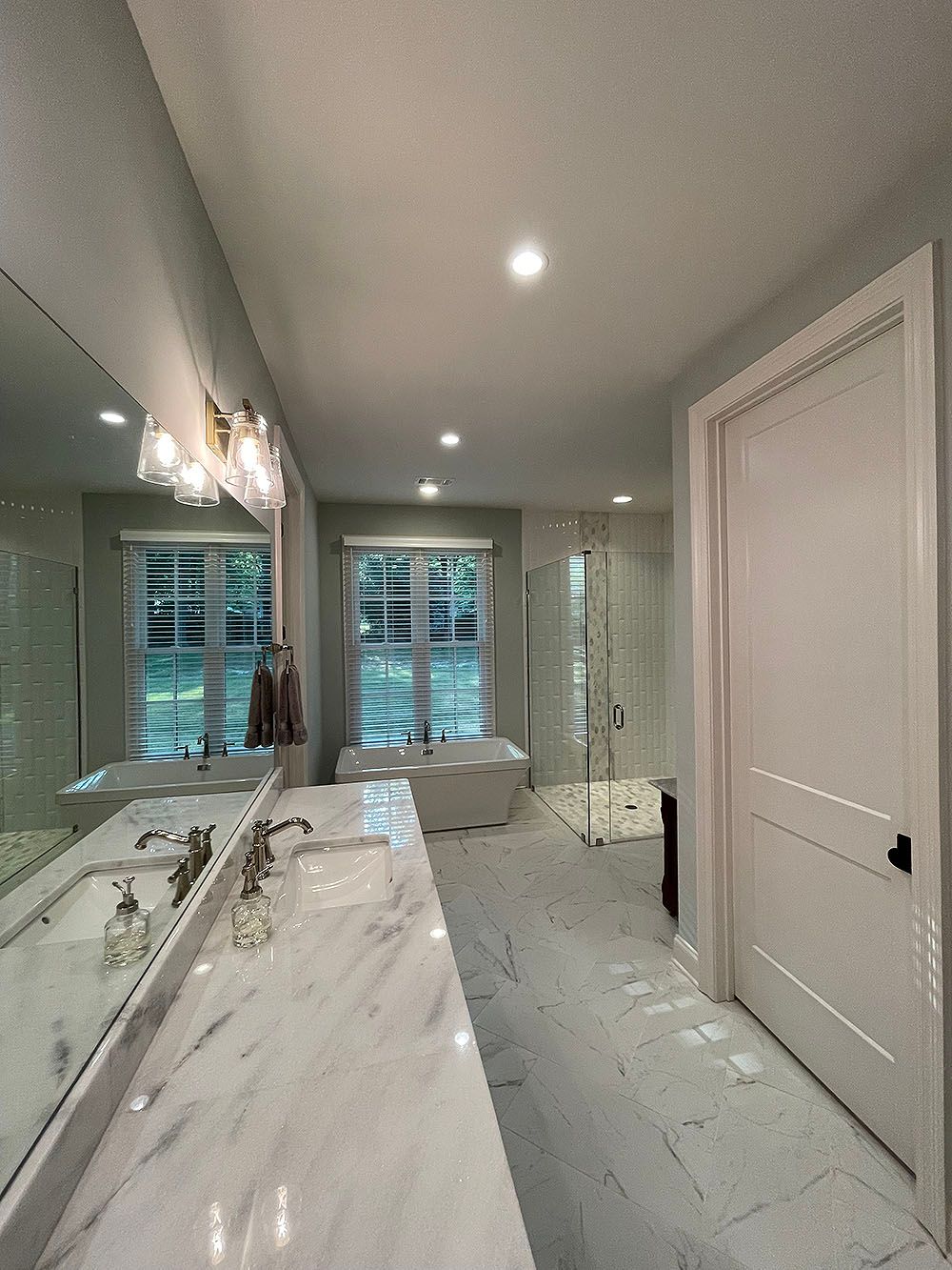 Master Bath 4 - Bathroom with marble countertop, double sinks, large mirror, shower, bathtub, and white door.