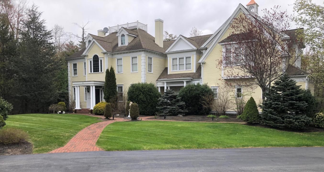 A large yellow house with a brick walkway leading to it.