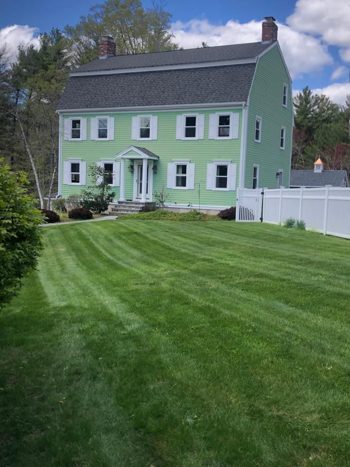 A green house with a lush green lawn in front of it.