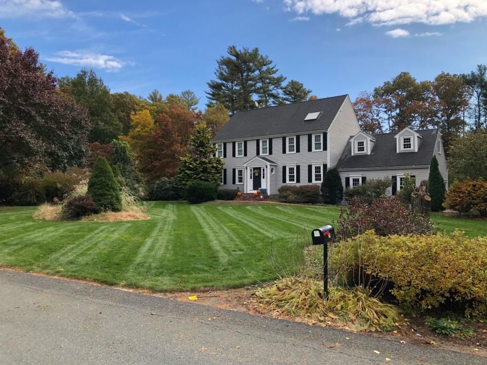 A large house with a lush green lawn and a mailbox in front of it.