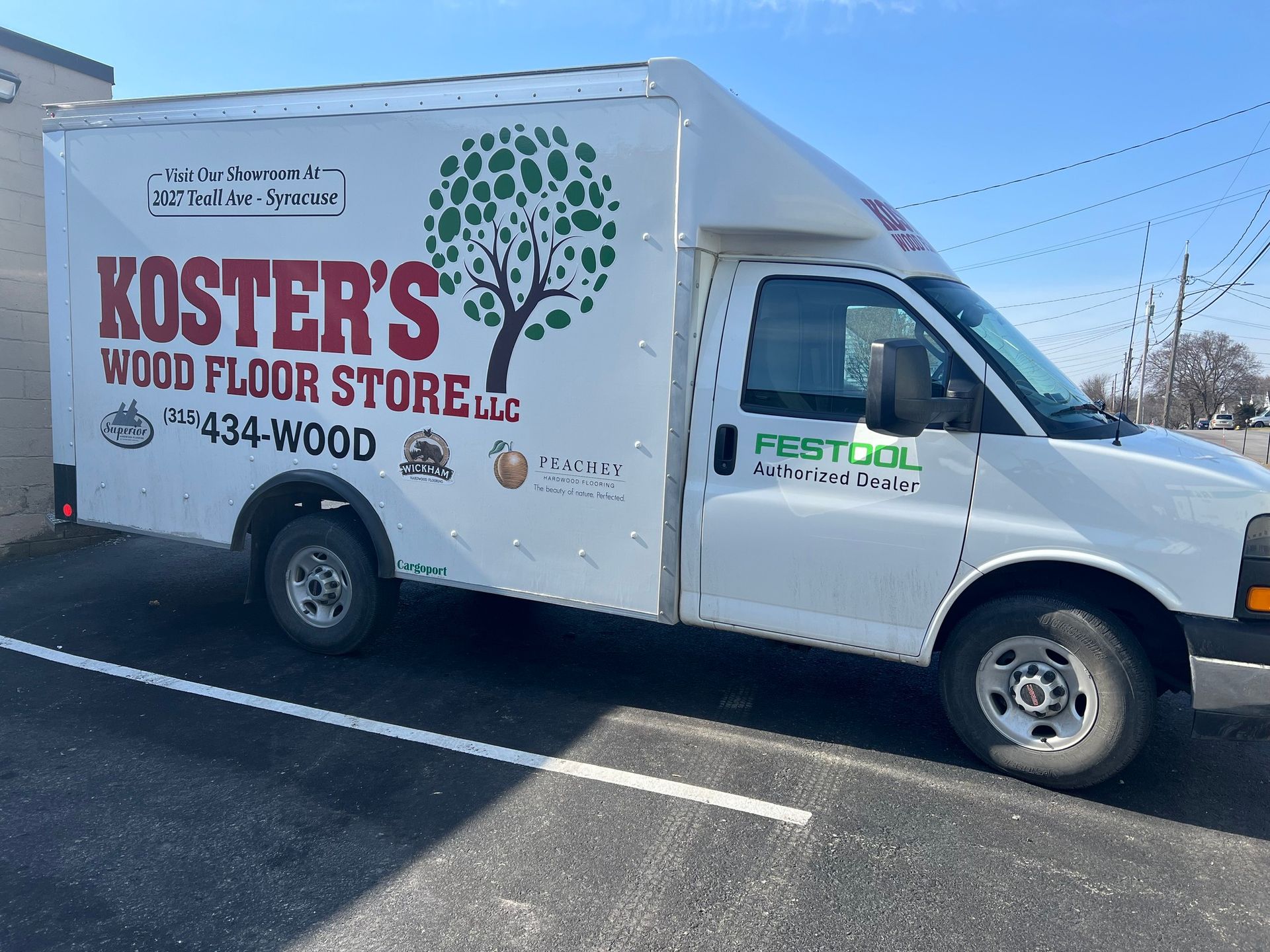 A white koster 's wood floor store van is parked in a parking lot