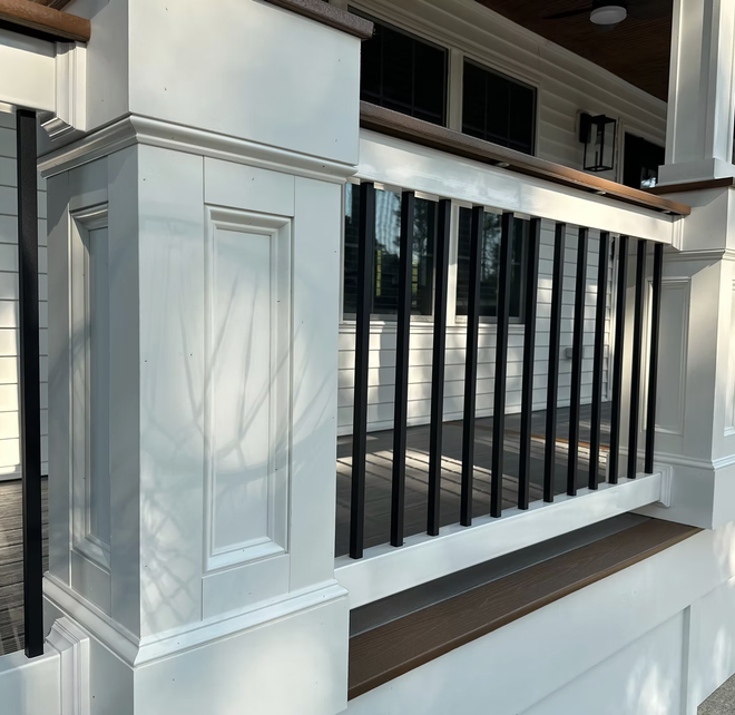 White porch railing with black vertical bars. Wooden trim on top.