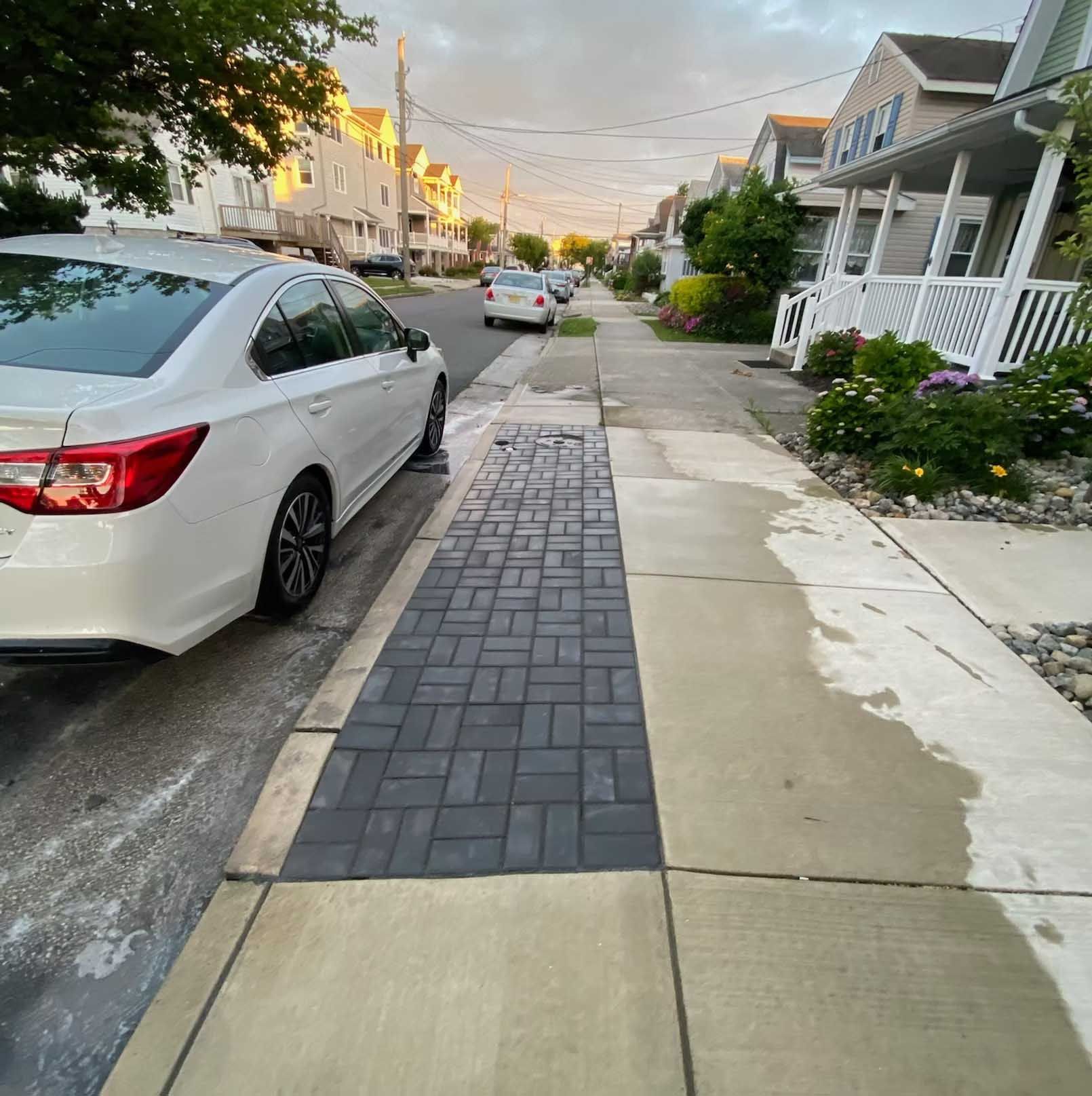 White car parked on street next to a brick paver walkway in front of houses; cloudy sky.