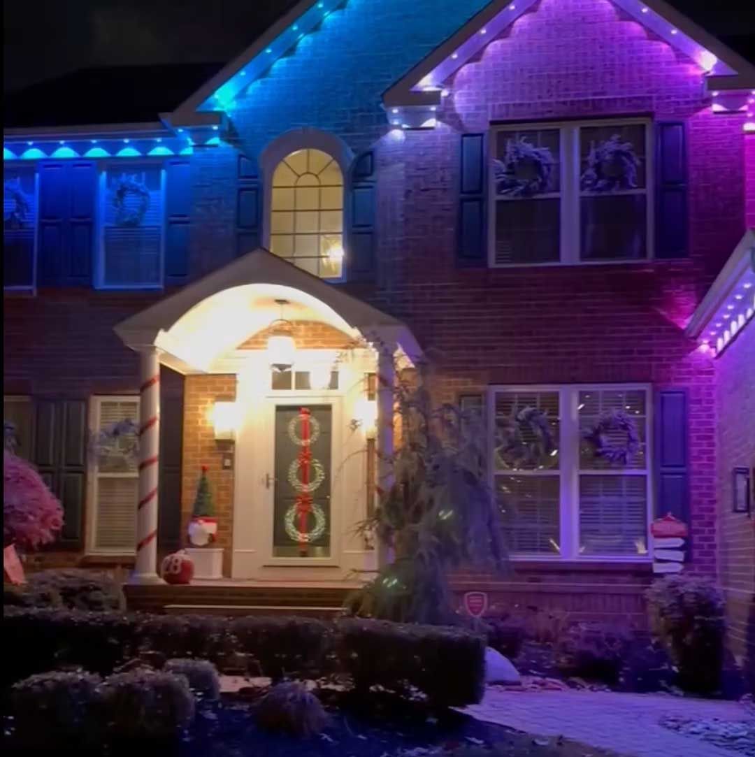 House at night decorated with blue and purple lights for the holidays.