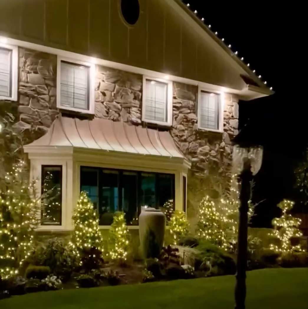 House with stone facade and holiday lights at night.
