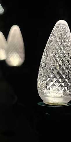 Close-up of a faceted, glowing, teardrop-shaped light against a black background.