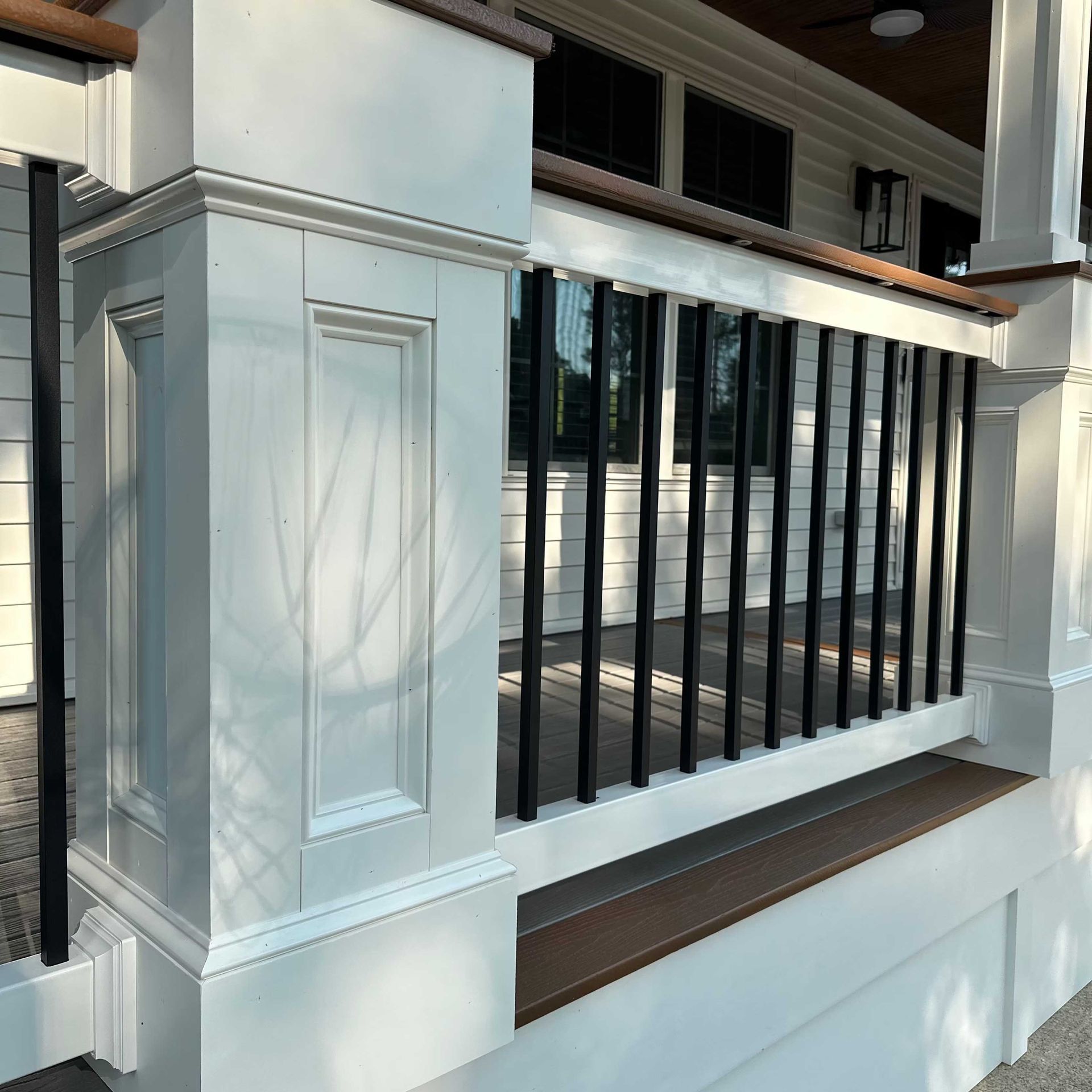 White porch railing with black vertical bars and brown trim.