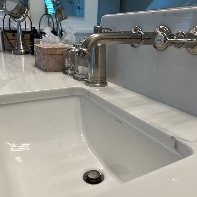 Close-up of a white bathroom sink with a silver faucet and marble countertop.