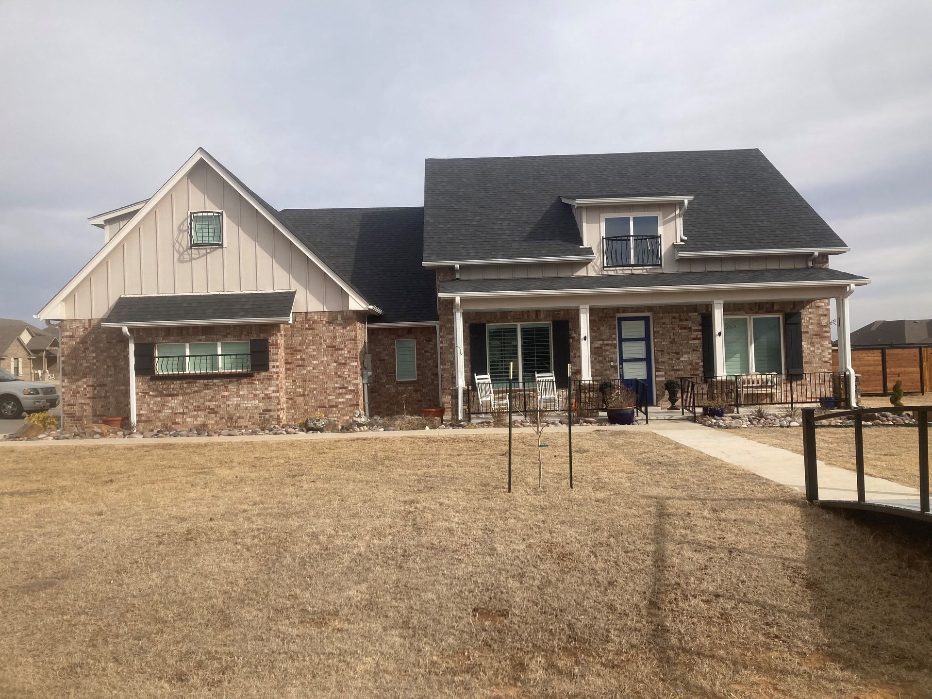 A large brick house with a black roof and a porch