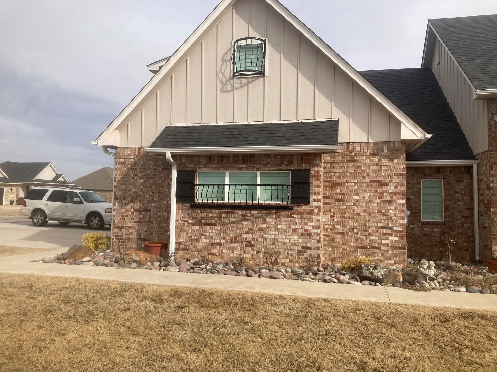 A white suv is parked in front of a brick house