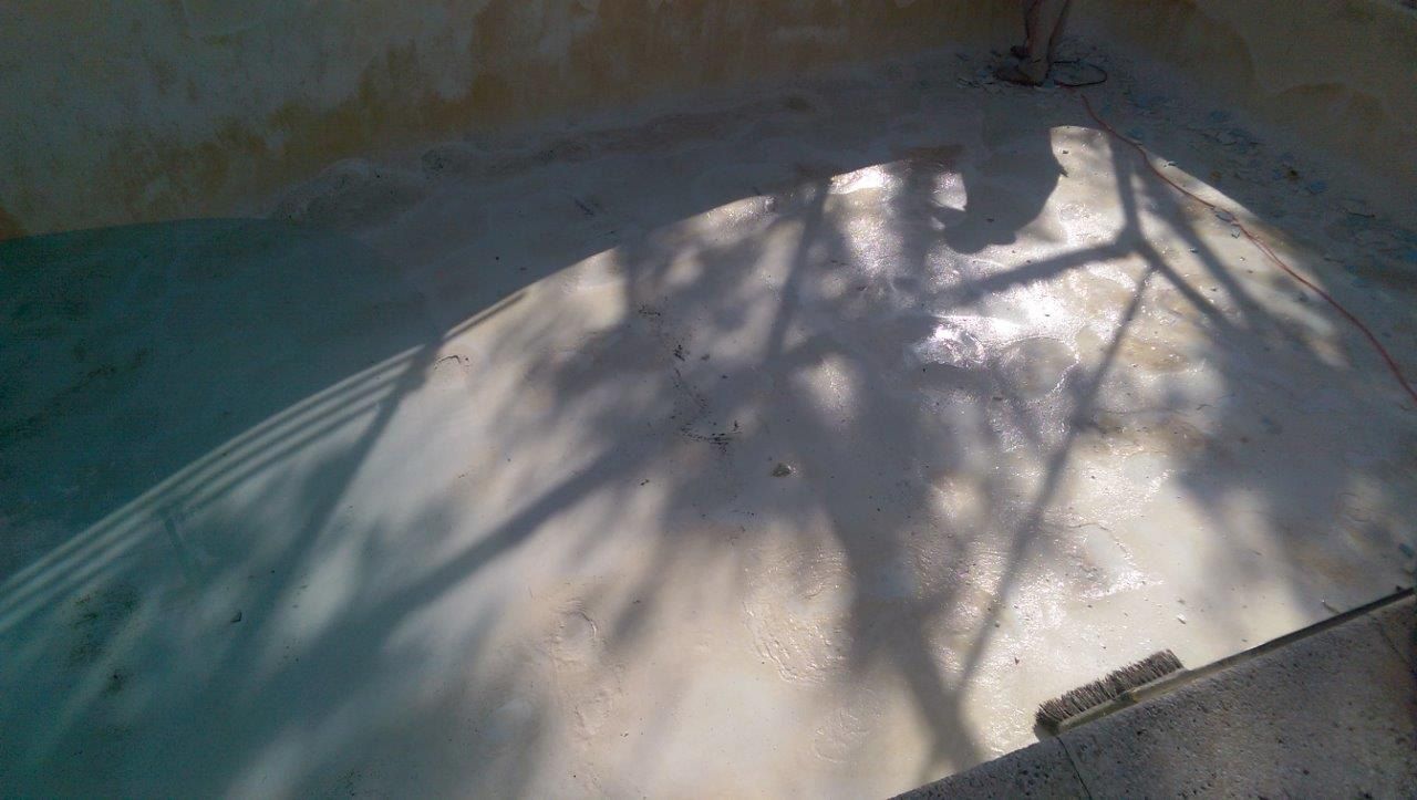 A concrete floor with intricate shadows cast by tree branches overhead, partially illuminated by natural light.