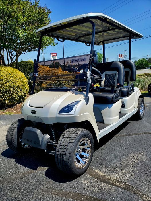 A green golf cart with a canopy is parked in a grassy field.