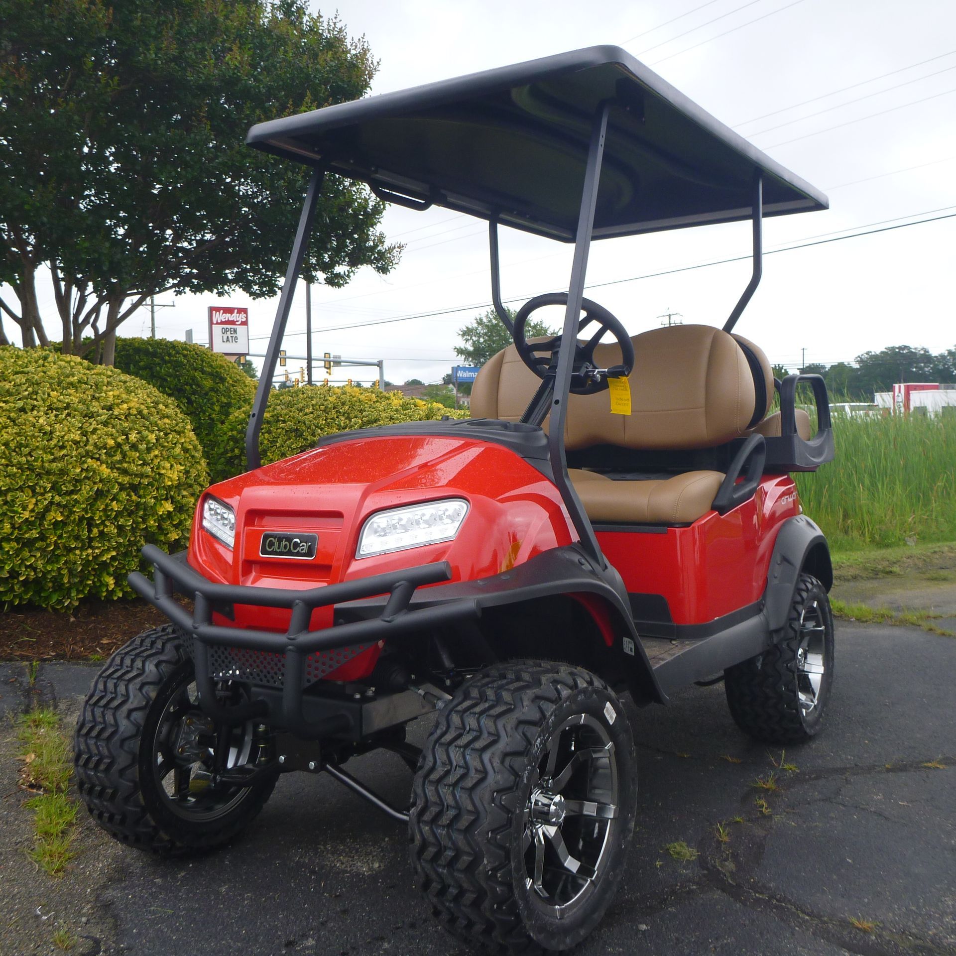 A red golf cart is parked in a parking lot