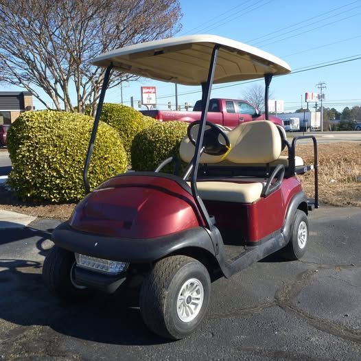 A red golf cart is parked in a parking lot