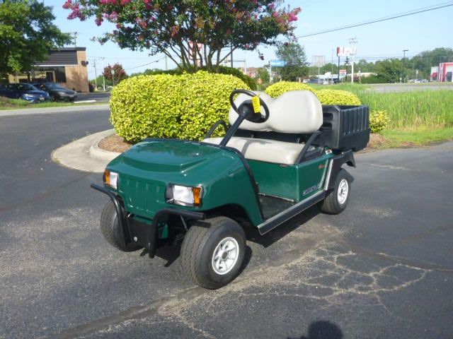 A green golf cart is parked in a parking lot