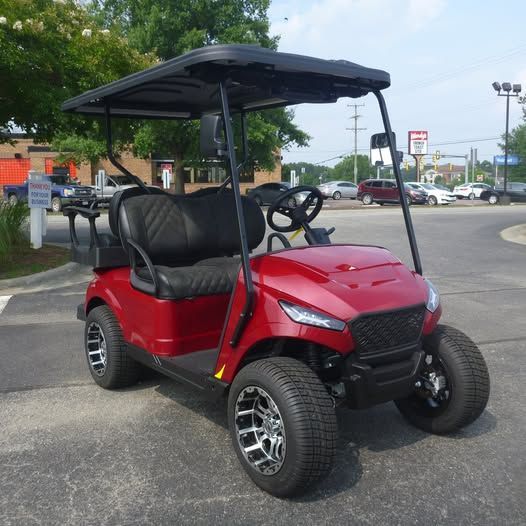 A red golf cart is parked in a parking lot