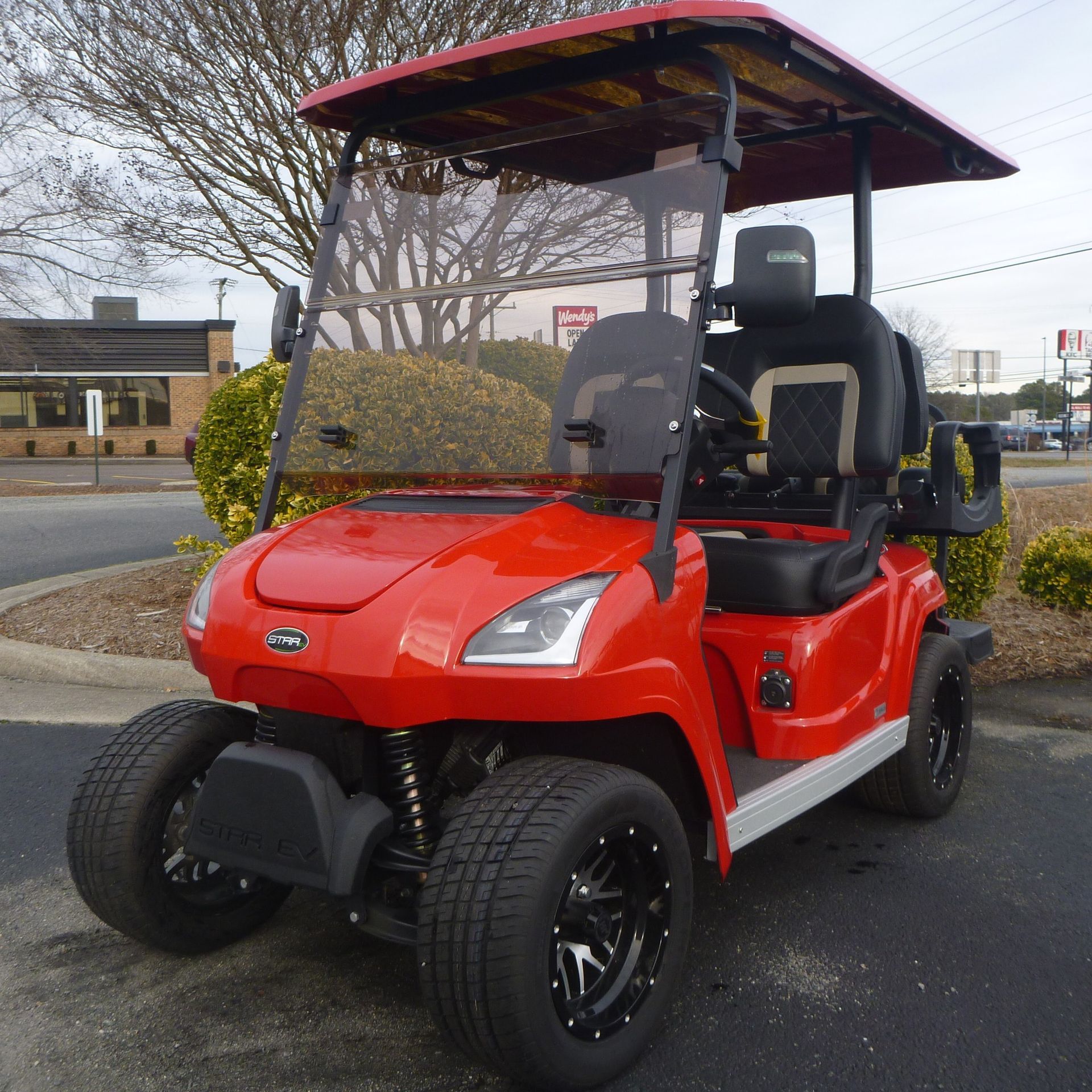 A red golf cart is parked in a parking lot