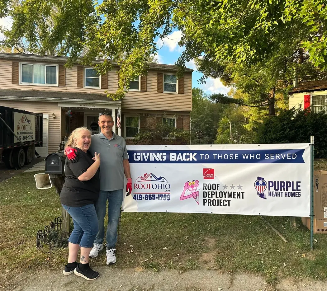 Two people stand in front of a banner that reads