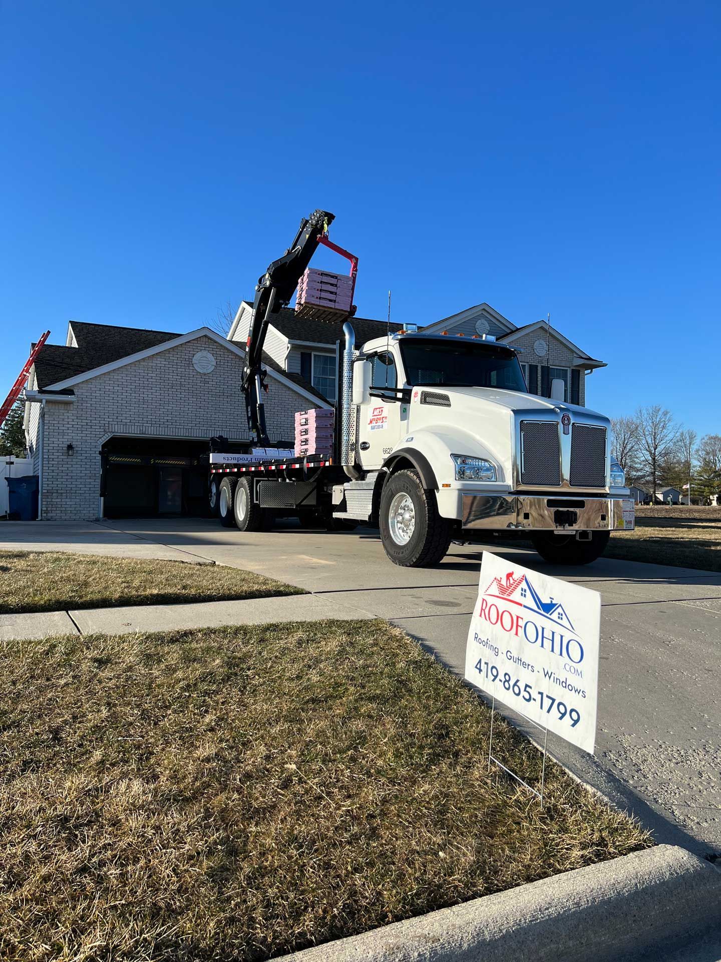 White utility truck unloading materials at a house under construction on a sunny day