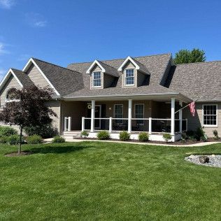 Suburban house with a covered front porch, manicured lawn, and blue sky