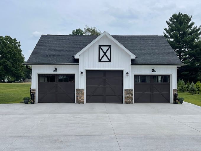 Three-car gray garage with white siding and dark roof on a concrete driveway