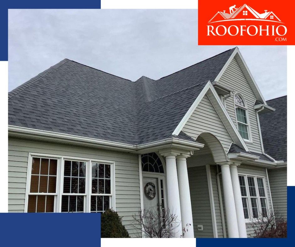 Gray-roofed suburban house with white trim and dormer windows, featuring a red RoofOhio logo in the top right.