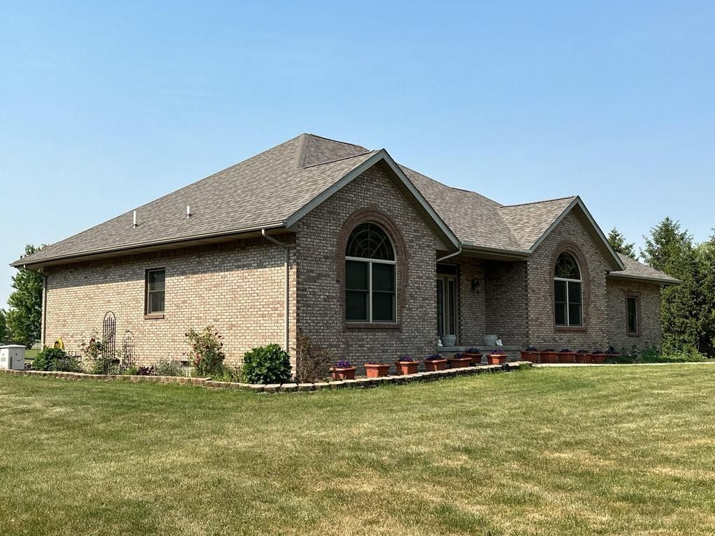 Single-story brick house with a large lawn under a clear blue sky