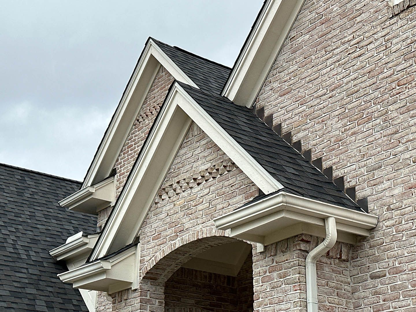 Brick house gable roof and covered front porch with white trim and gutters