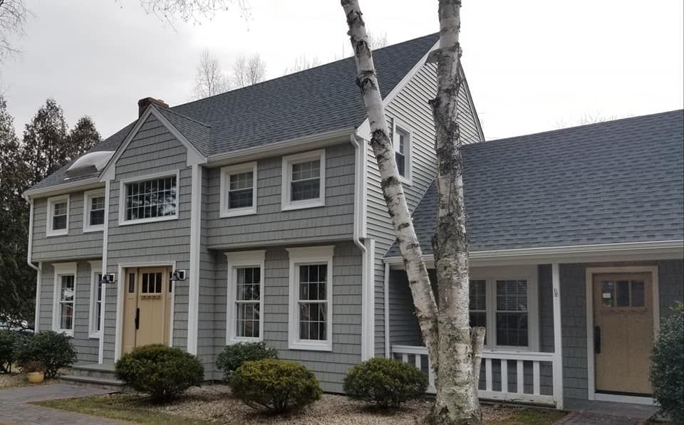 a large house with a gray siding and a black roof