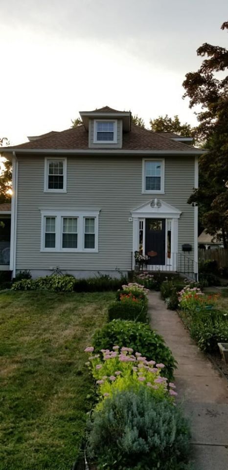 a large house with a lush green lawn and a walkway leading to it .