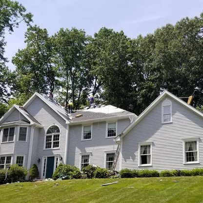 a large white house is sitting on top of a lush green hillside .