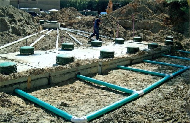 A man is walking in the dirt near a septic tank