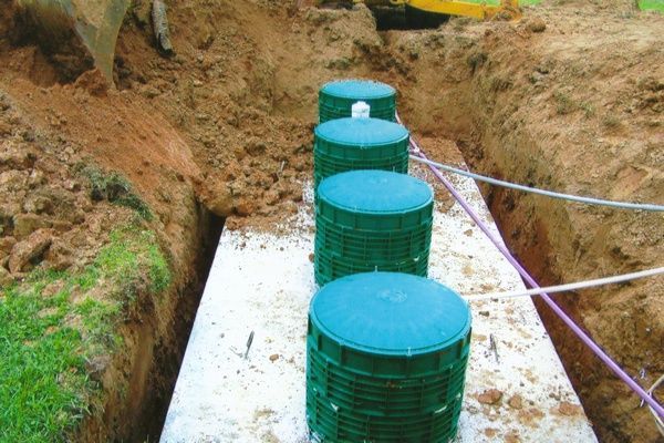A row of green containers are sitting in a trench.