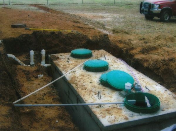 A septic tank is being built in the dirt next to a truck.