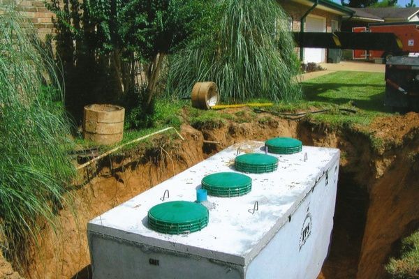 A septic tank is being installed in a yard next to a house.