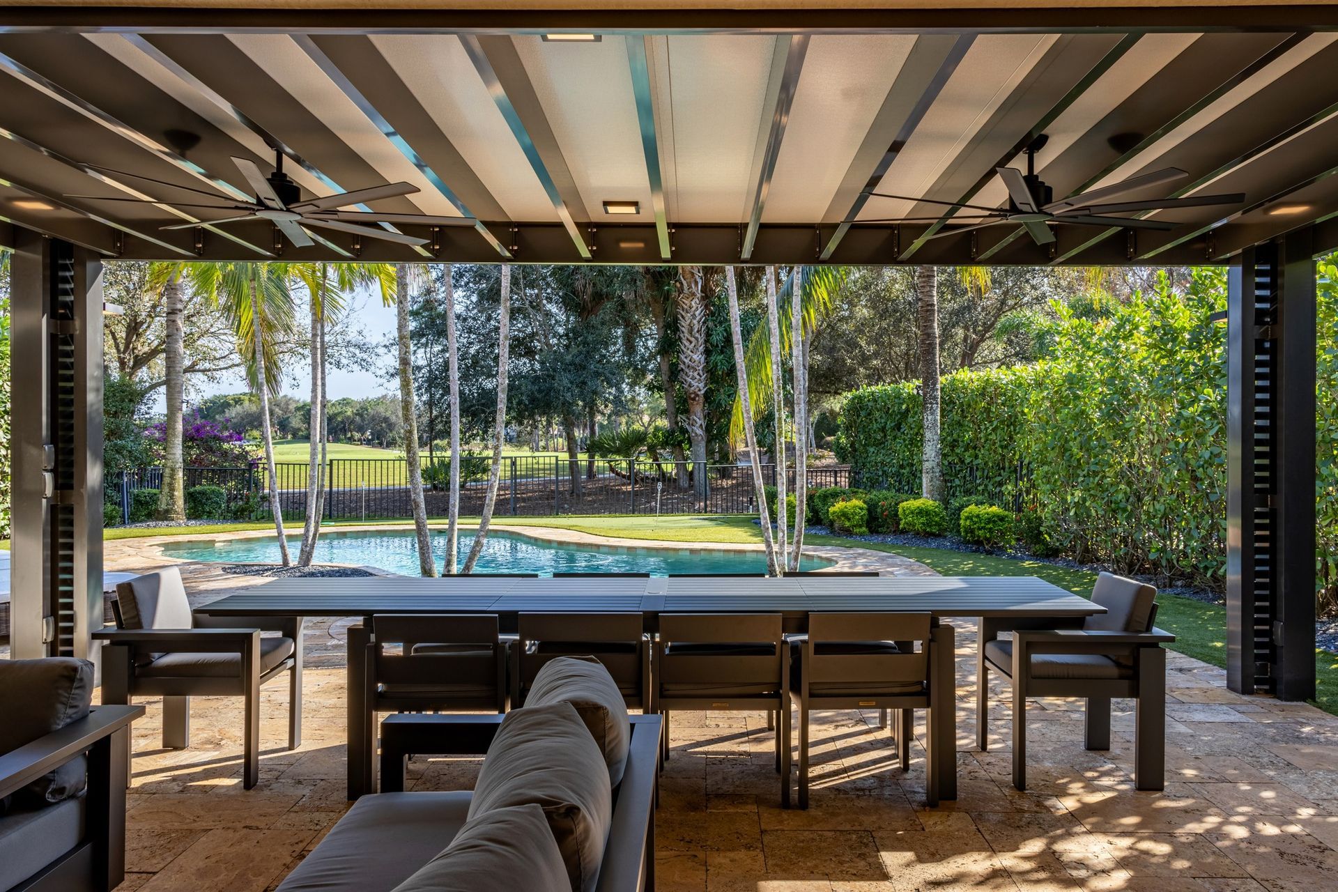 There is a large table and chairs under a pergola.