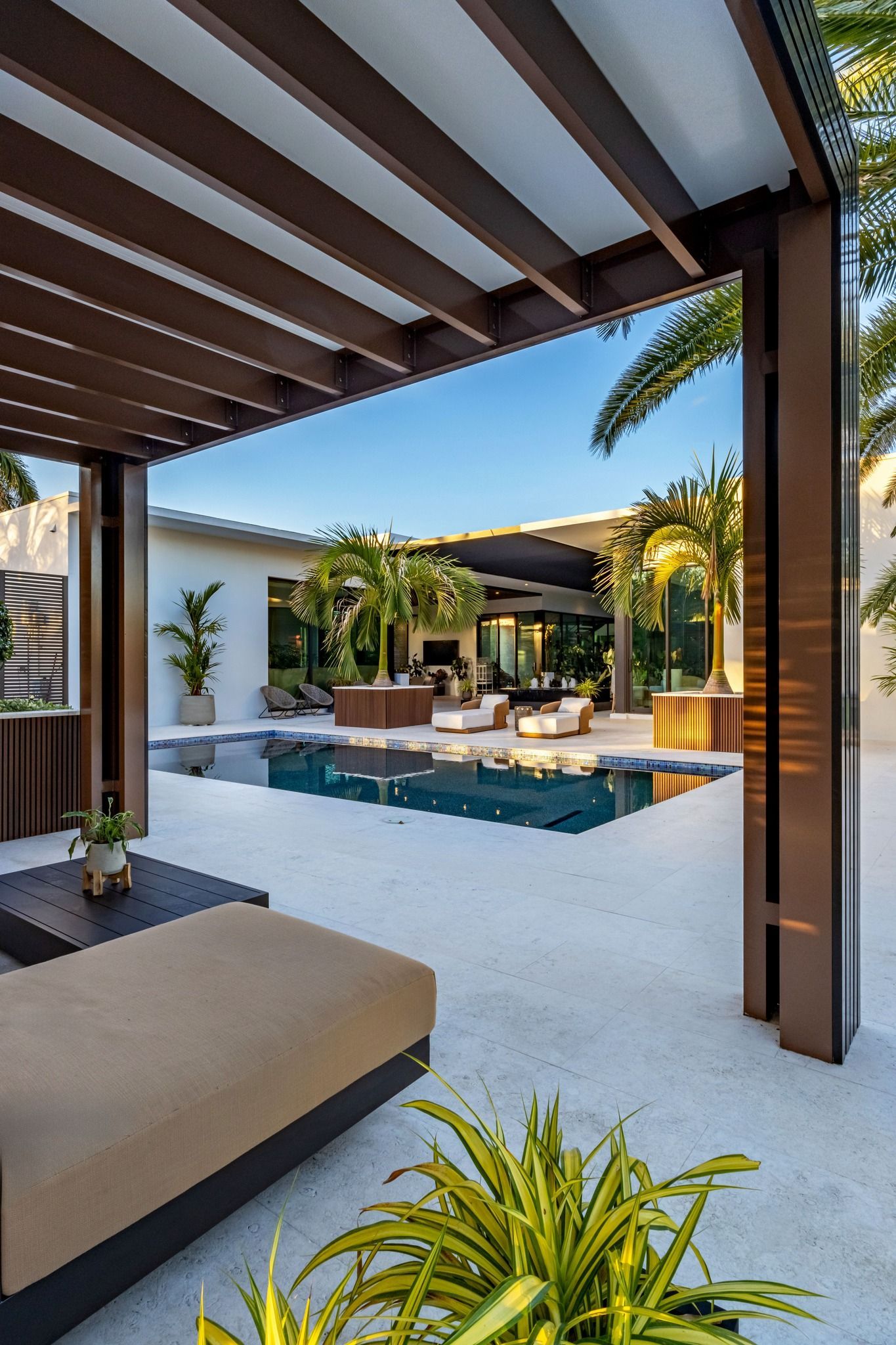 A view of a swimming pool from a pergola in a backyard.