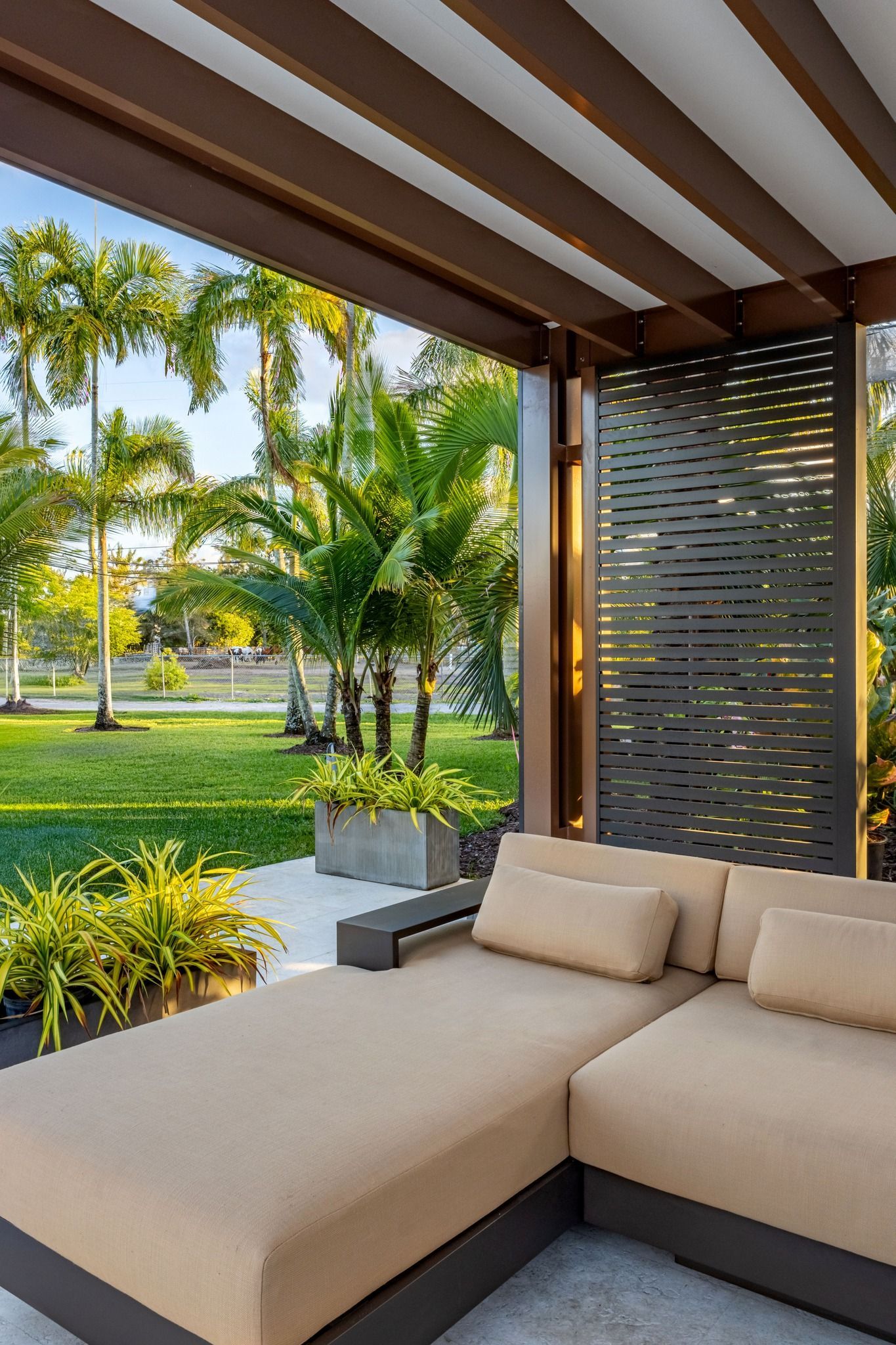A patio with a couch and a chair under a pergola.