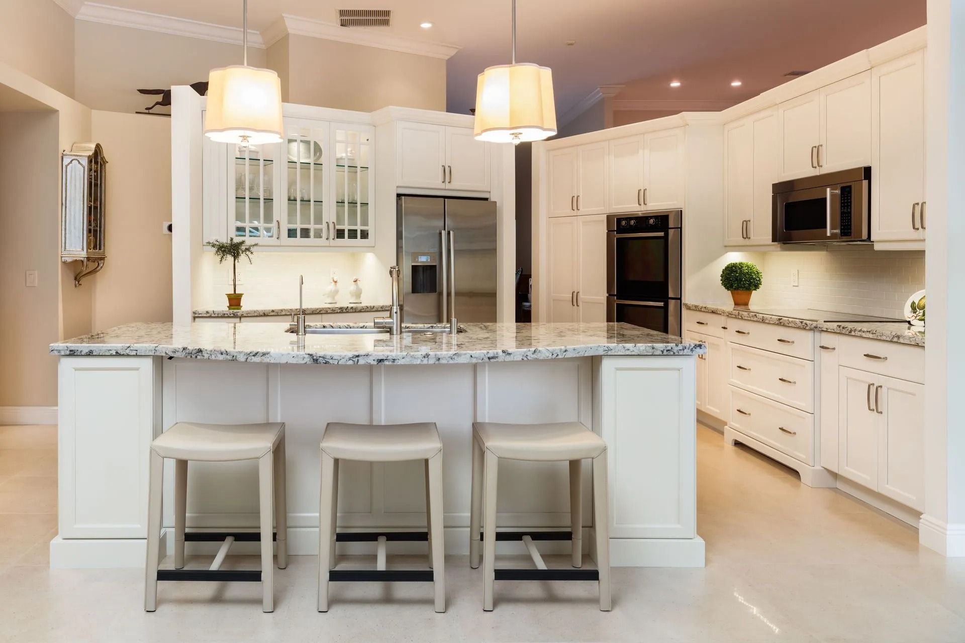 White kitchen with island seating and granite countertops.