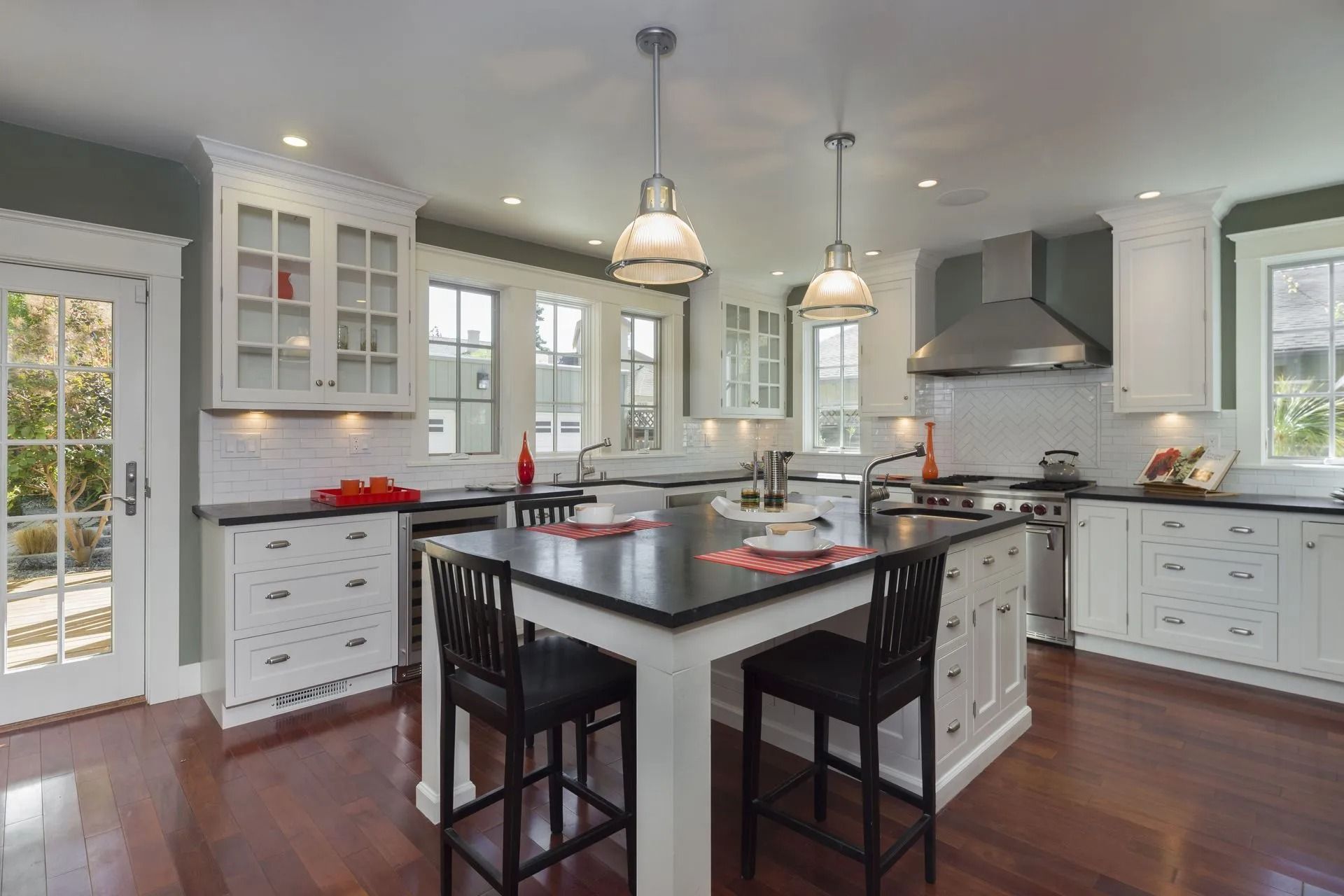 Kitchen with white cabinets, black countertops, and a central island with bar stools.