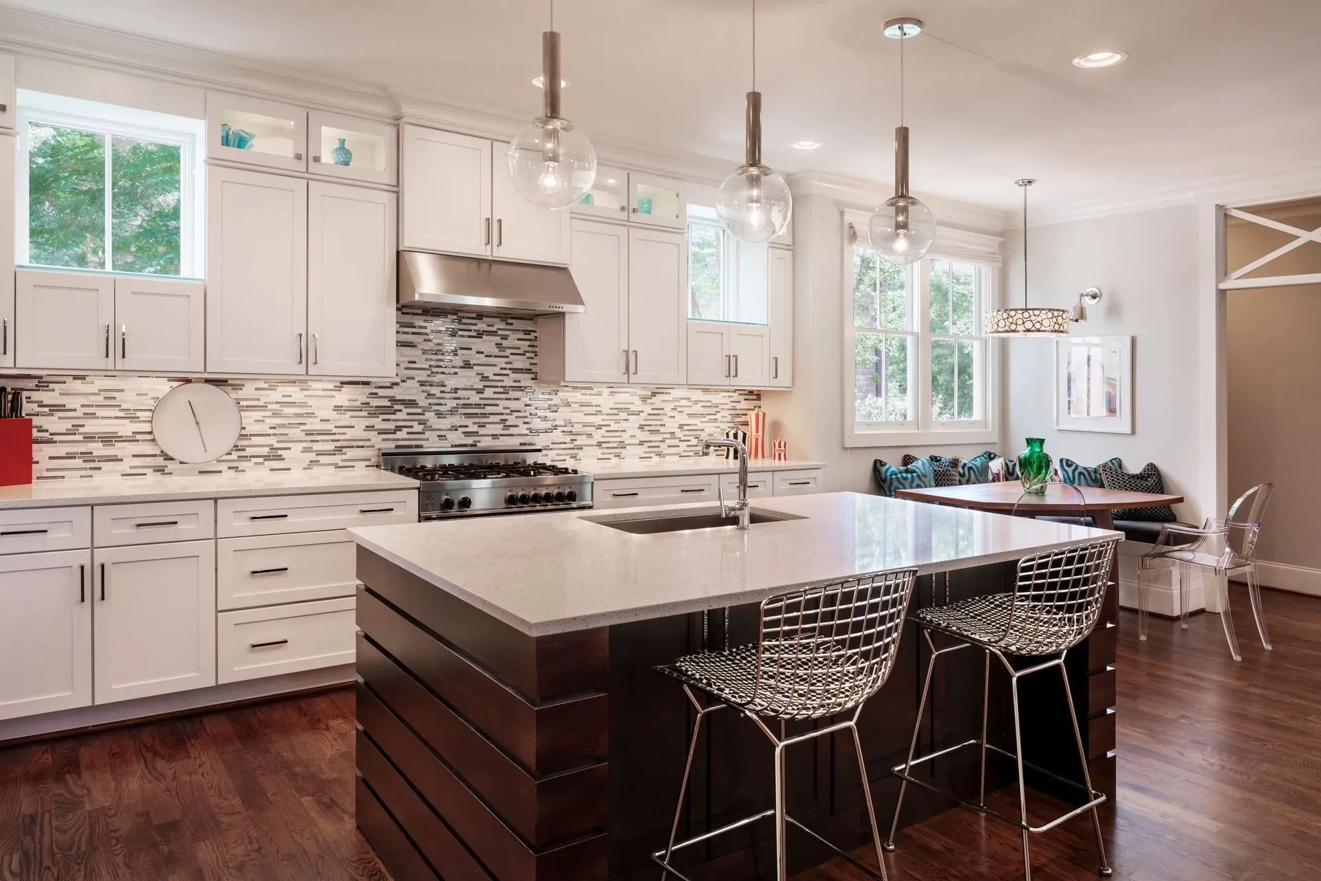 Modern kitchen with white cabinets, dark wood island, and pendant lights.