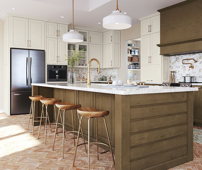 Kitchen with a light and dark color scheme. Island with stools, fridge, and overhead lights.